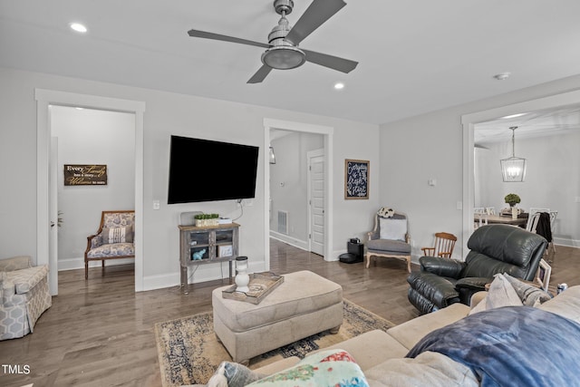 living room featuring wood-type flooring and ceiling fan with notable chandelier