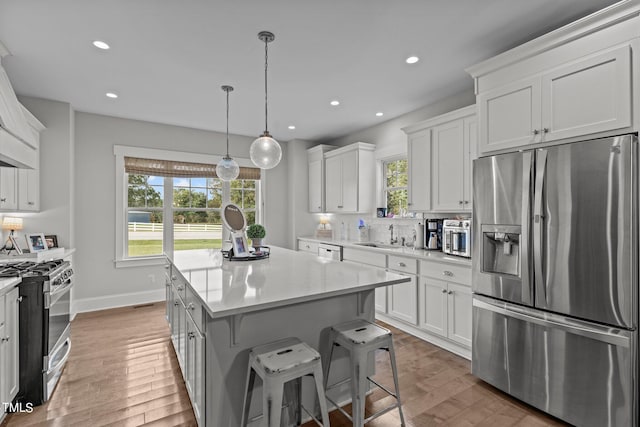 kitchen with appliances with stainless steel finishes, white cabinetry, and wood-type flooring