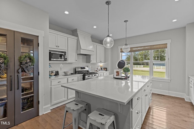 kitchen featuring custom exhaust hood, white cabinetry, stainless steel appliances, and a kitchen island