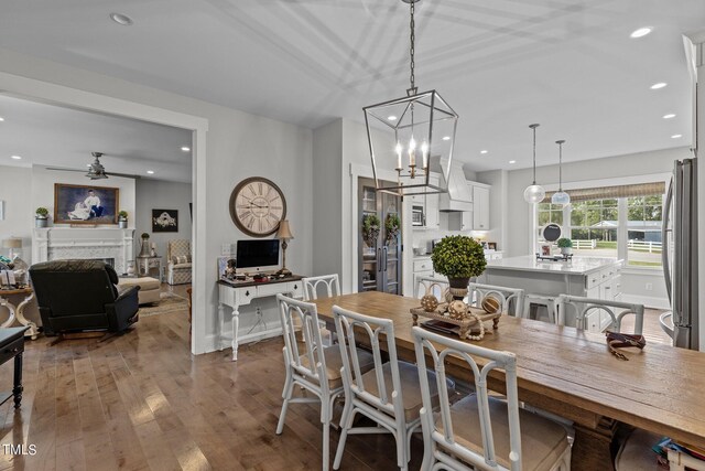 dining room with hardwood / wood-style floors and ceiling fan with notable chandelier