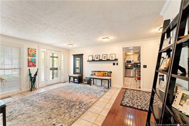 foyer featuring ornamental molding, light wood-type flooring, and a textured ceiling