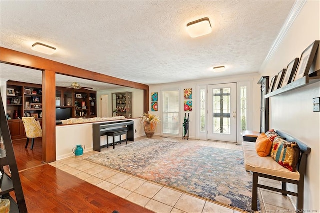 entrance foyer with ceiling fan, ornamental molding, light wood-type flooring, and a textured ceiling