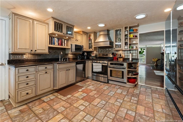 kitchen with custom exhaust hood, sink, tasteful backsplash, a textured ceiling, and appliances with stainless steel finishes