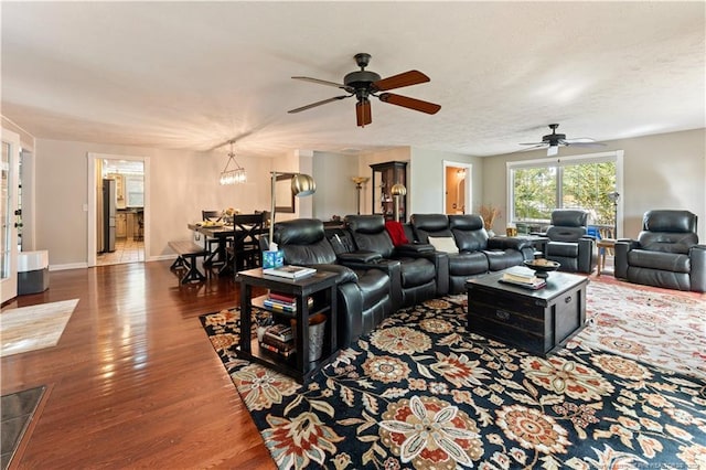 living room with a textured ceiling, ceiling fan with notable chandelier, and dark hardwood / wood-style floors