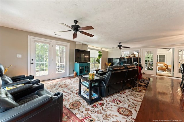 living room featuring a textured ceiling, ceiling fan, and light hardwood / wood-style flooring