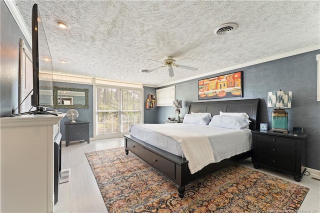 bedroom with ceiling fan, a textured ceiling, light hardwood / wood-style flooring, and crown molding