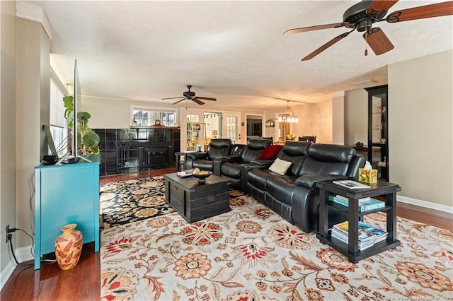 living room featuring ceiling fan with notable chandelier, hardwood / wood-style floors, and a textured ceiling