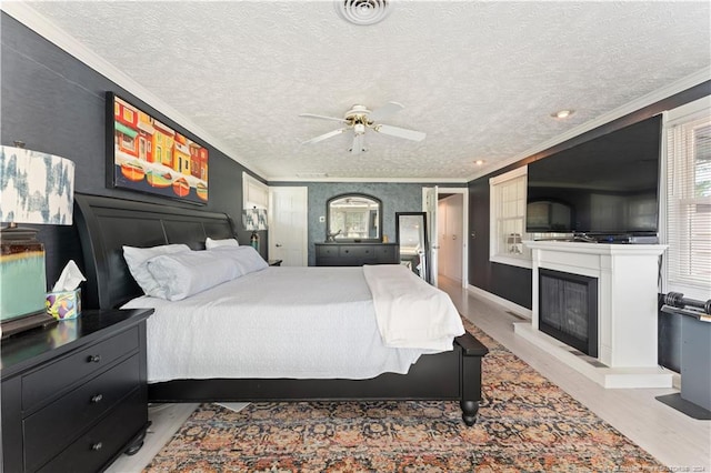 bedroom with ornamental molding, hardwood / wood-style flooring, a textured ceiling, and ceiling fan