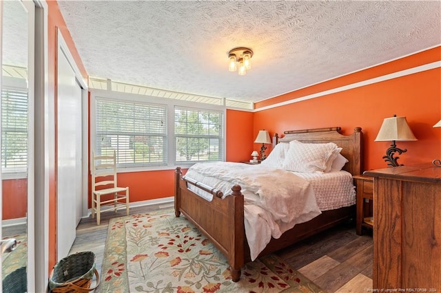 bedroom with a textured ceiling, hardwood / wood-style floors, and multiple windows