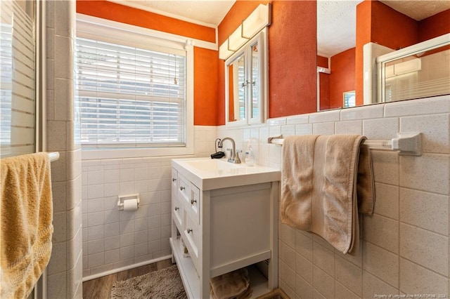 bathroom with a textured ceiling, hardwood / wood-style flooring, vanity, and tile walls