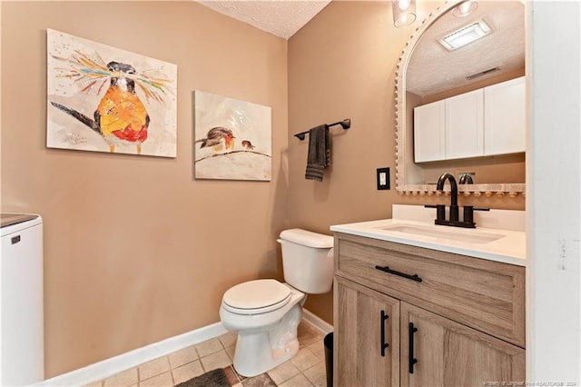 bathroom featuring vanity, toilet, a textured ceiling, and tile patterned floors