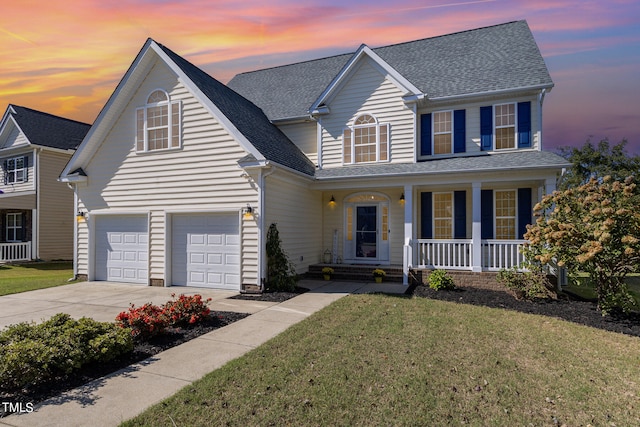 front facade featuring a yard, covered porch, and a garage