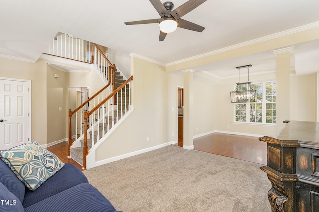 living room with crown molding, wood-type flooring, ceiling fan with notable chandelier, and decorative columns