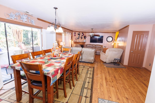 dining room with ornamental molding, light hardwood / wood-style floors, and ceiling fan with notable chandelier