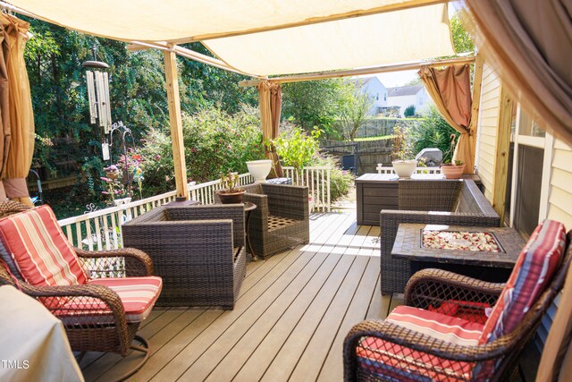 wooden terrace featuring an outdoor living space with a fire pit