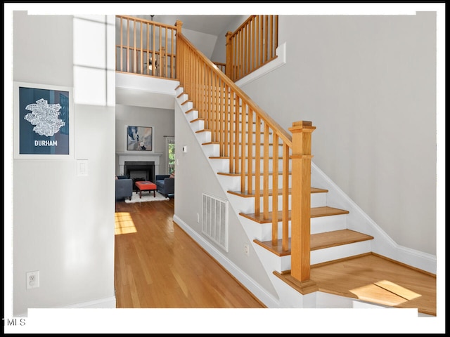 staircase with hardwood / wood-style flooring and a towering ceiling