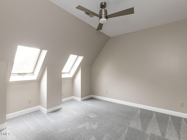 additional living space with light carpet, ceiling fan, and vaulted ceiling with skylight