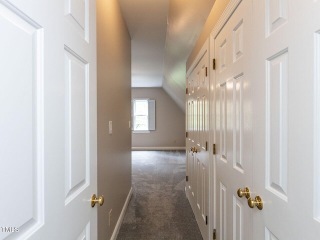 hall featuring dark carpet and vaulted ceiling