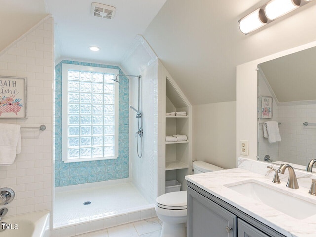 bathroom with toilet, a tile shower, vanity, and vaulted ceiling