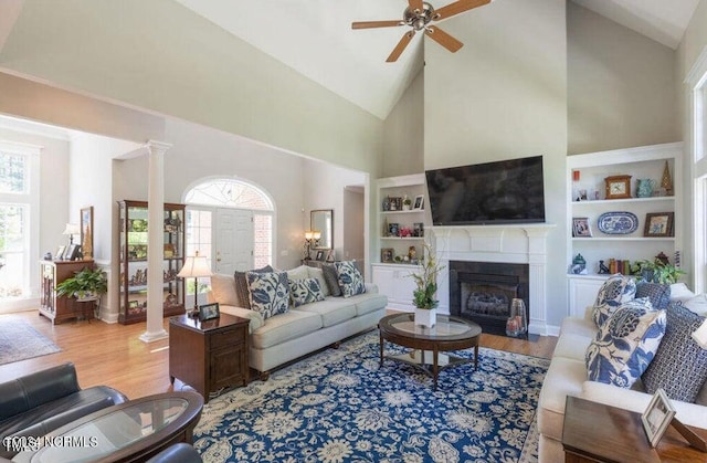 living room with hardwood / wood-style floors, built in shelves, high vaulted ceiling, and ceiling fan