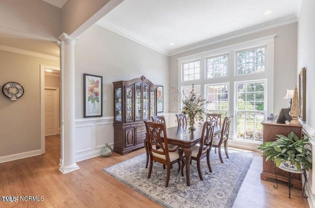 dining area with light hardwood / wood-style flooring, ornate columns, and crown molding