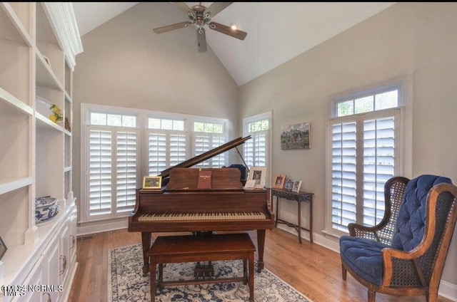 living area featuring high vaulted ceiling, light wood-type flooring, and ceiling fan