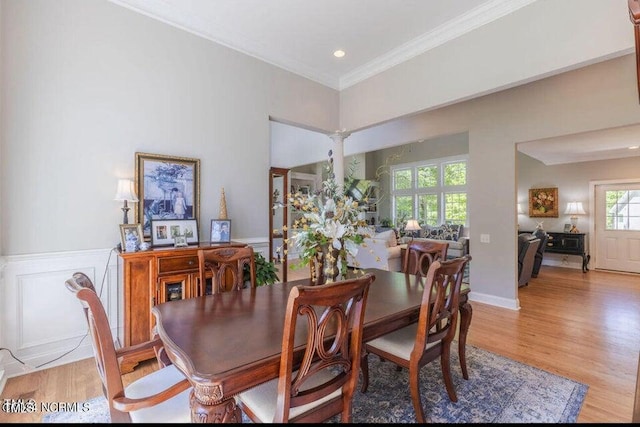 dining room with crown molding, ornate columns, and light wood-type flooring