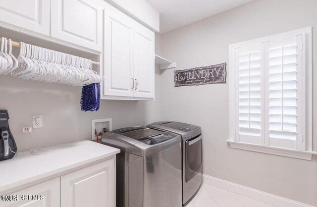 laundry room featuring washing machine and dryer, cabinet space, baseboards, and light tile patterned floors
