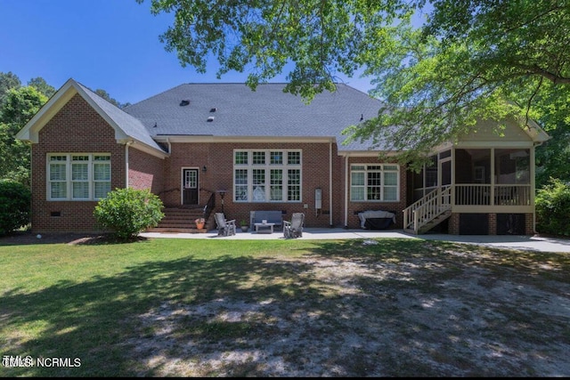 rear view of property featuring a sunroom, a patio area, brick siding, and a lawn