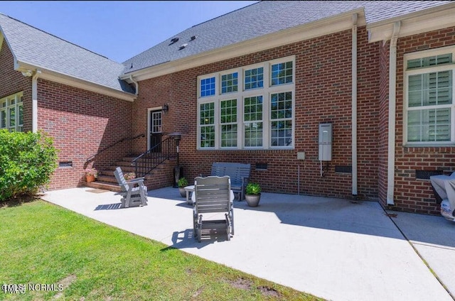 back of property featuring a patio, brick siding, a shingled roof, and crawl space