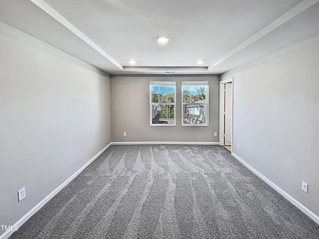 empty room with a raised ceiling and carpet floors