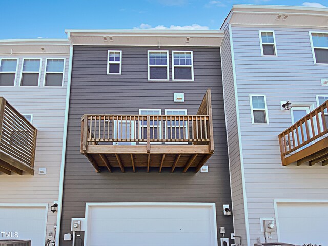 rear view of house featuring cooling unit, a balcony, and a garage