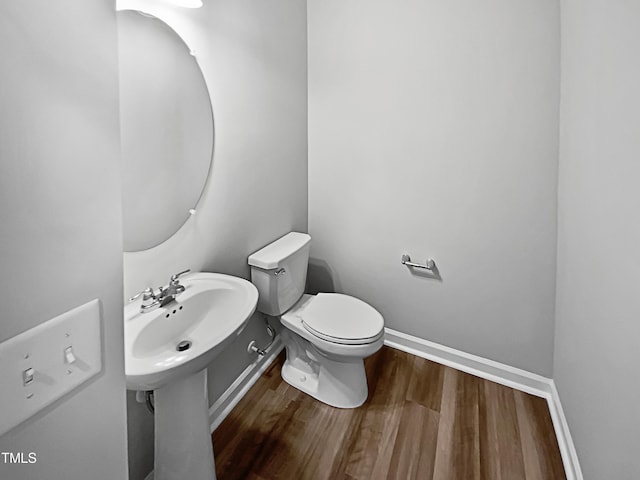 bathroom featuring toilet, wood-type flooring, and sink