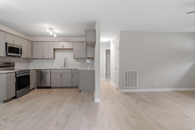 kitchen featuring appliances with stainless steel finishes, gray cabinetry, light hardwood / wood-style floors, and sink