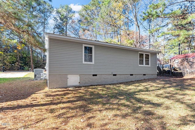 view of side of property with central AC and a lawn