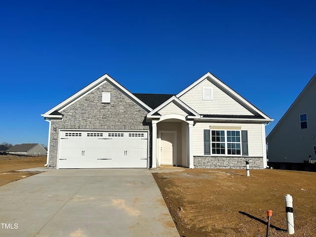 view of front of home featuring an attached garage, stone siding, and concrete driveway