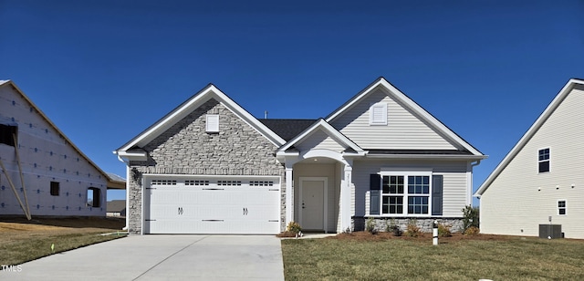 view of front of property with driveway, a garage, stone siding, central air condition unit, and a front yard