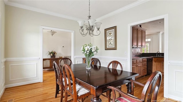 dining area with ornamental molding, a chandelier, sink, and light wood-type flooring