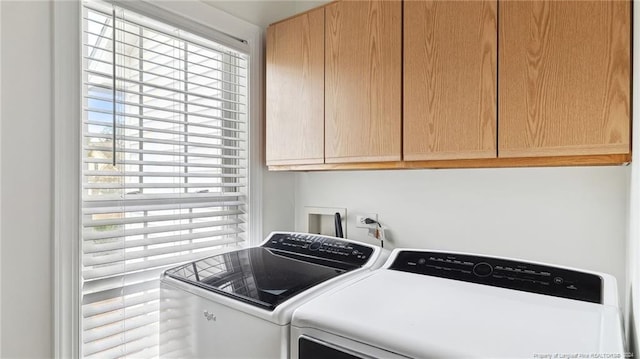 laundry room featuring cabinets, a wealth of natural light, and separate washer and dryer