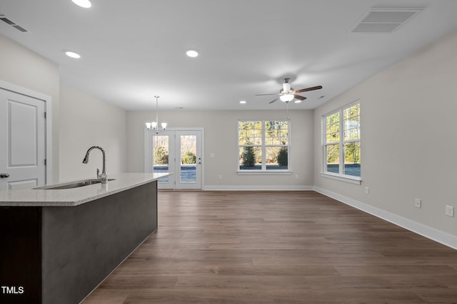 kitchen with a kitchen island with sink, ceiling fan with notable chandelier, hanging light fixtures, sink, and dark hardwood / wood-style floors