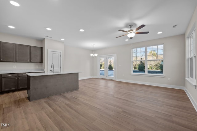 kitchen featuring hardwood / wood-style floors, french doors, ceiling fan with notable chandelier, sink, and decorative light fixtures