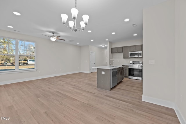 kitchen featuring a center island with sink, light hardwood / wood-style flooring, pendant lighting, and appliances with stainless steel finishes