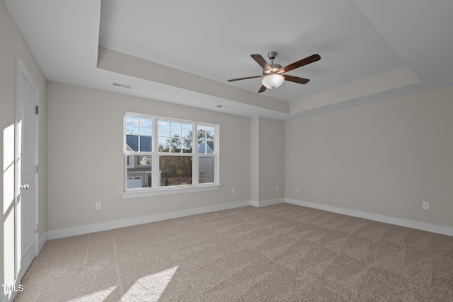 empty room featuring a tray ceiling, ceiling fan, and light colored carpet