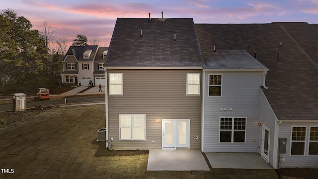 back house at dusk with cooling unit and a patio