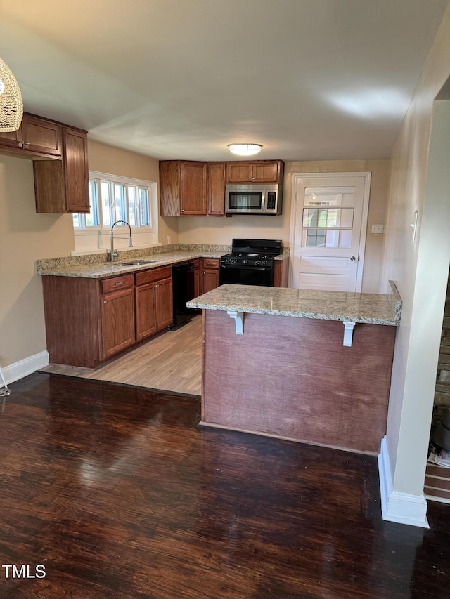 405 Whitfield Dr, Goldsboro, NC 27530 - kitchen featuring black appliances, a sink, wood finished floors, and light stone countertops