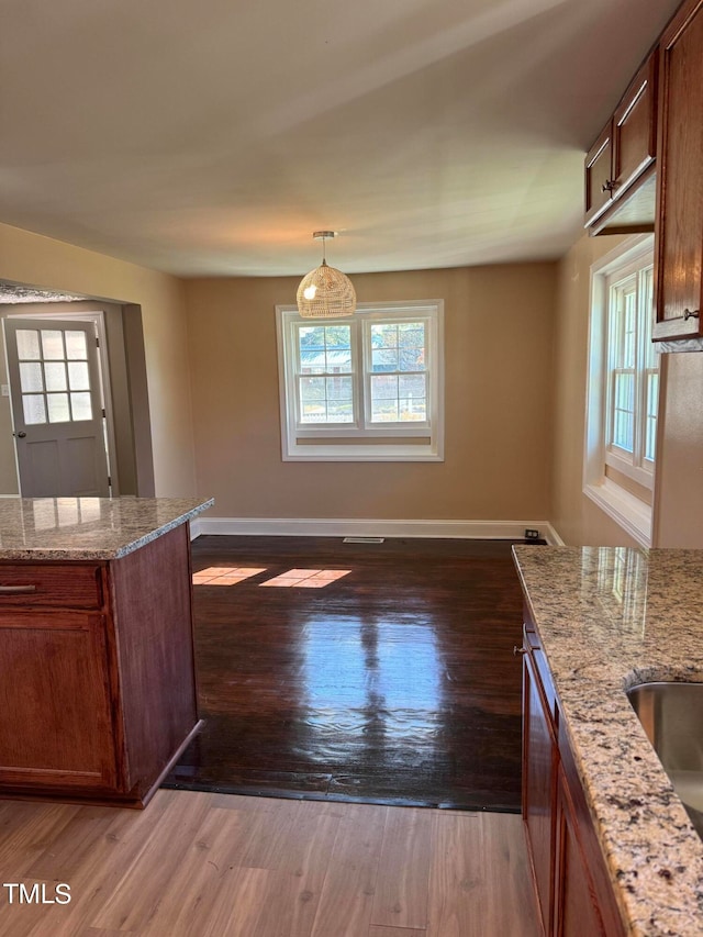 kitchen with a wealth of natural light, pendant lighting, and dark hardwood / wood-style flooring