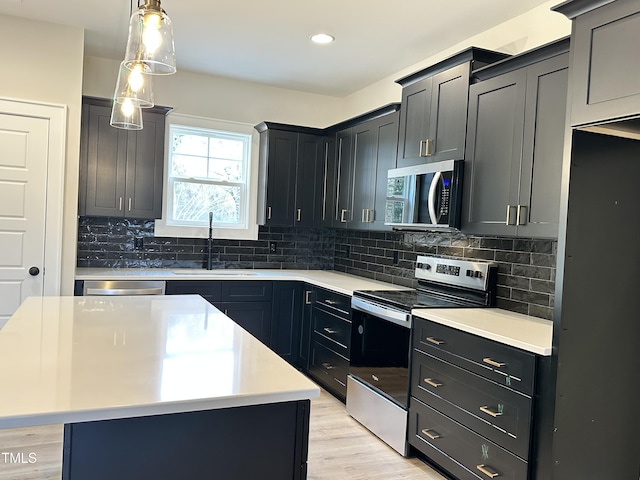 kitchen with sink, a center island, stainless steel appliances, and light wood-type flooring