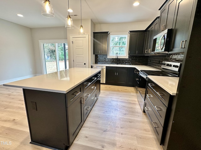 kitchen with appliances with stainless steel finishes, tasteful backsplash, sink, a center island, and light hardwood / wood-style floors