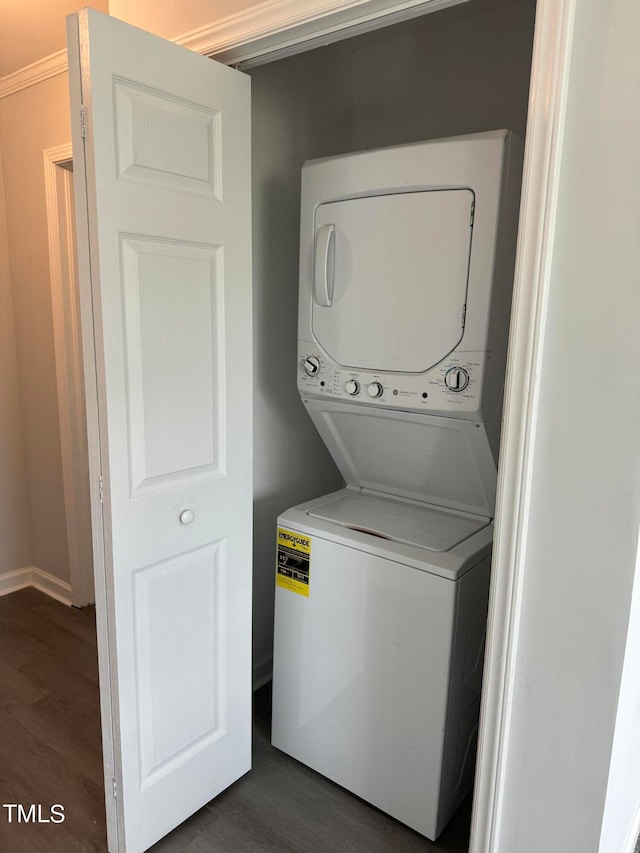 laundry room featuring stacked washing maching and dryer, crown molding, and dark hardwood / wood-style flooring