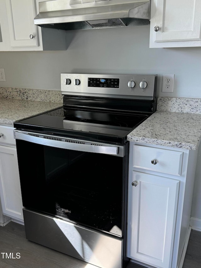 kitchen featuring stainless steel electric stove, exhaust hood, white cabinetry, light stone countertops, and dark wood-type flooring